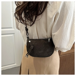 Detail of dark brown crescent crossbody bag featuring matte texture and knotted strap