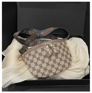 Close-up of beige canvas chest bag with monogram patterns in a luxury gift box packaging