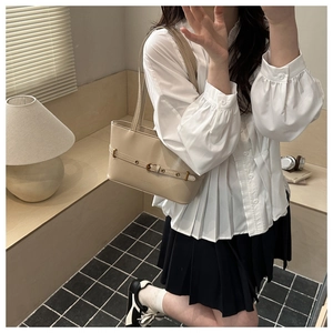 Detail of beige faux leather shoulder bag with buckle strap in cozy interior setting