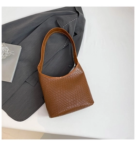 Detail of brown woven texture bucket bag with contrast white stitching and minimalist design