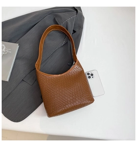 Detailed view of the brown woven texture and wide shoulder strap on this large hobo bag