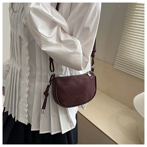 Detail of dark burgundy half-moon crossbody bag with soft matte texture and logo