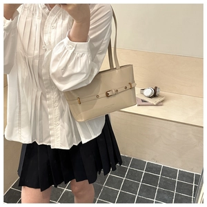 Detail of a cream rectangular shoulder bag with metal eyelet strap in a casual campus setting