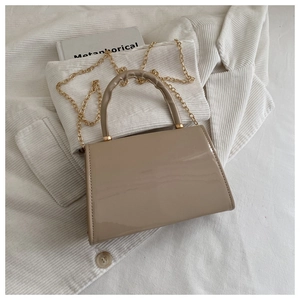 Detailed view of a stylish khaki patent leather handbag with a gold chain strap