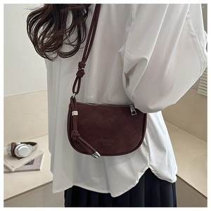 Close-up of matte dark red semi-round crossbody bag with unique knotted strap detail