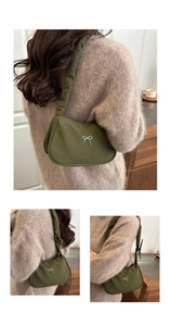Detail of dark green nylon underarm bag with silver bow and ruffled strap on shoulder