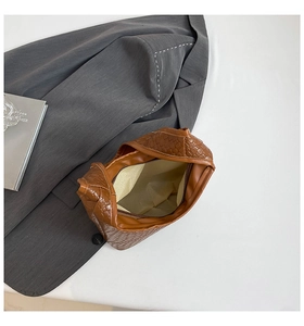 Detail of woven handbag showing interior lining, zip pocket, and brown faux leather texture