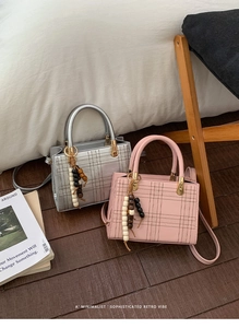 Detailansicht quadratischer Handtaschen in Silber und Rosa mit Perlenanhängern und Trageriemen