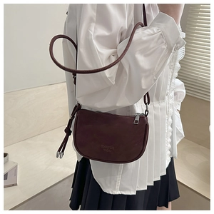 Detail view of the deep red saddle bag showing matte leather texture and knotted strap
