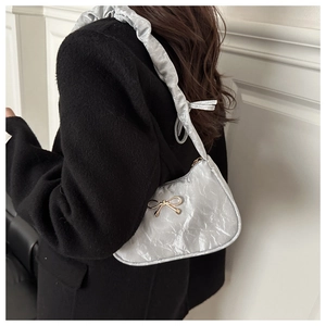 Close-up of pleated silver hobo bag with a gold butterfly buckle and ruched shoulder strap