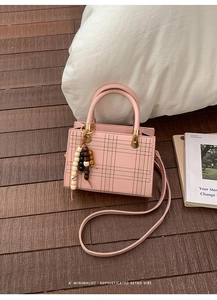 Détail du sac bandoulière rose avec coutures croisées et breloque en perles de bois