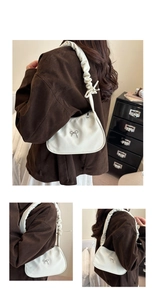 Detail of cream white leather underarm bag with silver bow and ruffled strap