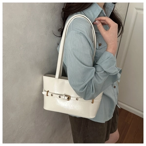 Model wearing a white leather tote bag with retro buckle strap and brand logo