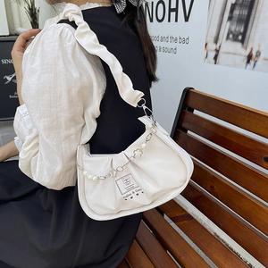 White pleated underarm bag with pearl chain and floral charms on a female model