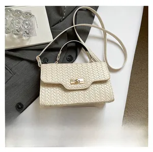 Détail du sac à main crème à texture tressée avec fermoir doré et poignée élégante