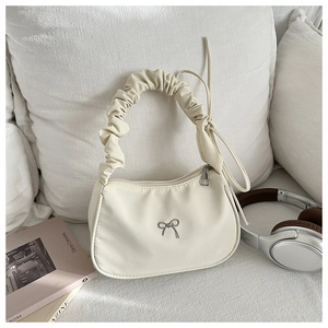 Close-up of pleated handle and silver bow detail on the cream pleated shoulder bag