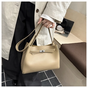 Detalle de un bolso trapecio de cuero beige con cierre giratorio plateado y correas