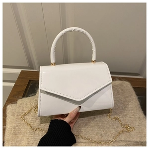 Detailed close-up of glossy white patent leather handbag with gold metal hardware