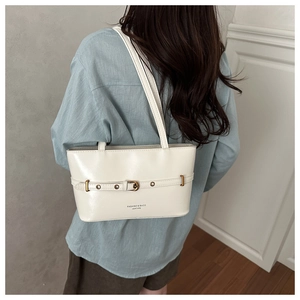 Model view of cream leather shoulder bag with gold hardware and trapezoid shape