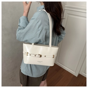 Detailed view of cream PU leather tote bag featuring buckle strap and elegant metallic eyelets