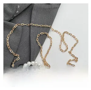 Close-up of elegant gold chain and white pearl shoulder straps for women's handbags