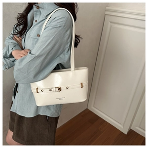 Close-up of white glossy shoulder bag with belt buckle detail and fashion text print