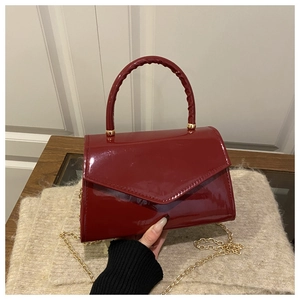 Detail shot of glossy red patent leather bag with elegant V-shaped stitching and gold chain