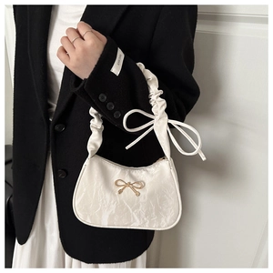 Détail du sac croissant plissé blanc avec nœud doré et élégantes lanières à rubans