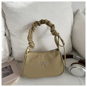 Detail of khaki pleated underarm bag with silver butterfly accent and satin sheen