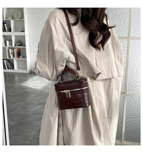 Detail of red crocodile embossed mini box bag worn cross-body on a beige coat