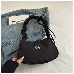 Detail of black nylon underarm bag with silver bow buckle and ruched handle design