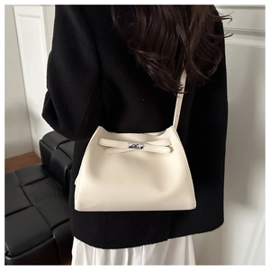 Elegante bolso de hombro en cuero beige con hebilla metálica llevado por modelo