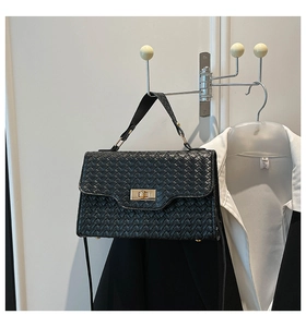 Détail d'un sac à main noir en cuir tressé avec fermoir doré et fine bandoulière