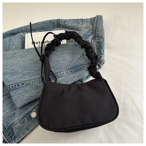 Detail of black half-moon shoulder bag with pleated cloud handle and side drawstring knot