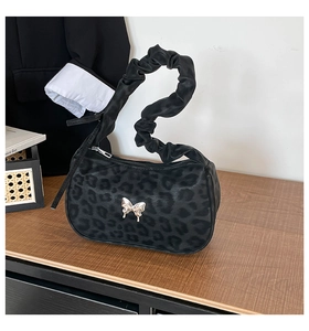 Close-up of leopard print texture with silver butterfly ornament and scrunchie handle