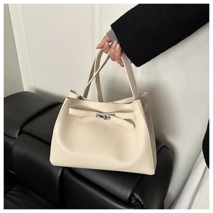 Detalle del bolso cubo en cuero blanco crema con lazo decorativo y cierre de metal plateado
