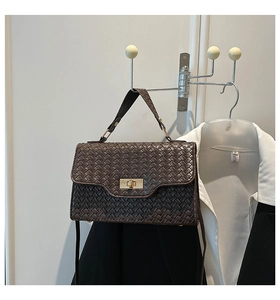 Détail de la texture en cuir tressé marron foncé et fermoir doré du sac à main