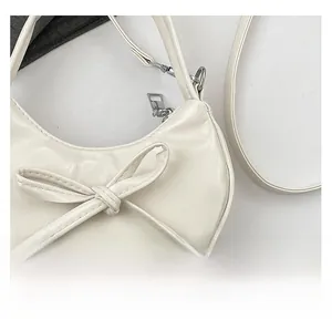 Dettaglio della borsa a mezzaluna in pelle crema con fiocco e perle metalliche argento