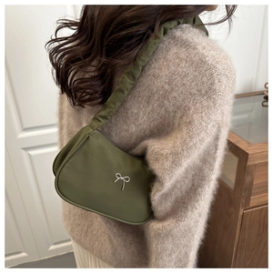 Detail of dark green satin shoulder bag with pleated strap and silver bow ornament