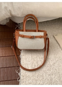 Vue détaillée d'un sac rétro en cuir marron et toile beige posé sur un tapis
