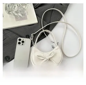 Piccola borsa a mezzaluna crema accanto a uno smartphone per mostrarne le dimensioni
