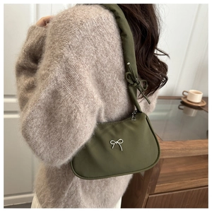 Olive green hobo bag with bow detail and knotted strap shown on model in cozy setting