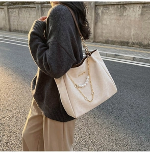 Dettaglio della borsa tote in pelle crema con eleganti catene di perle e oro