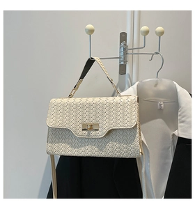 Détail d'un sac à main tissé crème avec fermoir rotatif et poignée supérieure