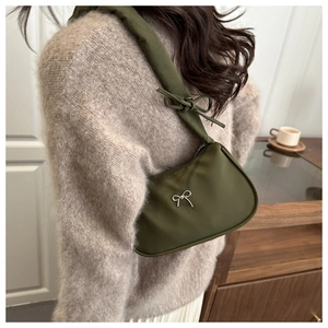 Detail of dark green shoulder bag with silver bow ornament and padded strap design