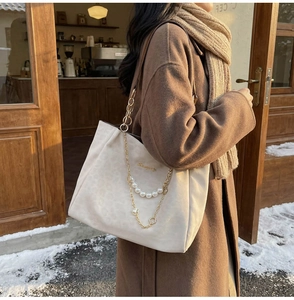 Dettaglio borsa tote vintage con stampa leopardata, catena dorata e ciondolo di perla