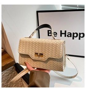 Détail d'un sac à main tressé blanc cassé avec fermoir doré et bandoulière réglable