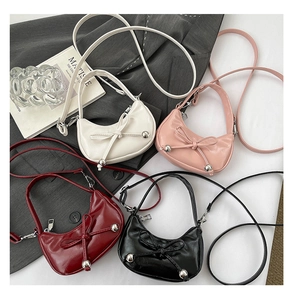 Collection of bow crescent bags in white, pink, burgundy, and black glossy leather