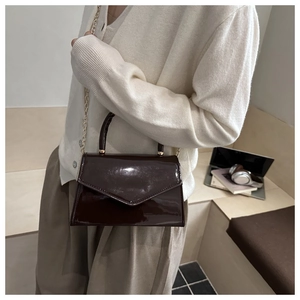 Dettaglio borsa a mano in vernice marrone scuro con catena dorata e tracolla chic