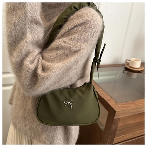 Close-up of olive green nylon crescent bag with silver metallic bow detail on shoulder